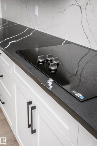 Kitchen view of dark countertops, black electric stovetop, and white cabinets - 804 Elderberry Crest, Edmonton, AB - Indoor Photo Showing Other Room