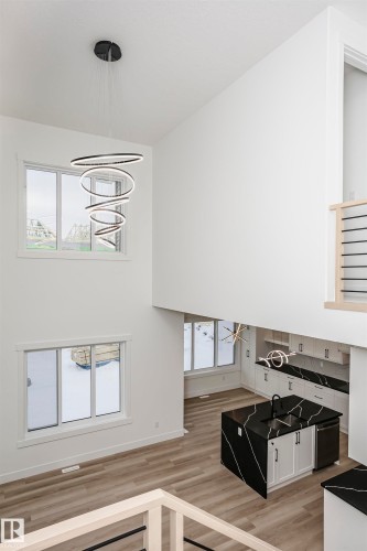 Stairway featuring healthy amount of natural light, wood finished floors, a towering ceiling, and a chandelier - 804 Elderberry Crest, Edmonton, AB - Indoor Photo Showing Other Room