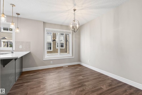 Unfurnished dining area featuring dark wood finished floors, a chandelier, and a textured ceiling - 36 330 Bulyea Road, Edmonton, AB - Indoor Photo Showing Kitchen