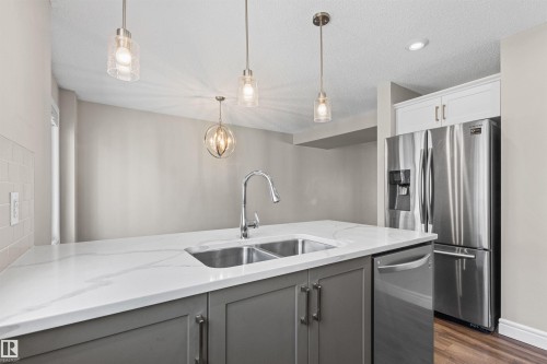 Kitchen with gray cabinetry, dark wood finished floors, stainless steel appliances, hanging light fixtures, and light stone counters - 36 330 Bulyea Road, Edmonton, AB - Indoor Photo Showing Kitchen With Double Sink With Upgraded Kitchen
