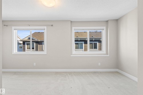 Unfurnished room with light carpet, healthy amount of natural light, and a textured ceiling - 36 330 Bulyea Road, Edmonton, AB - Indoor Photo Showing Other Room