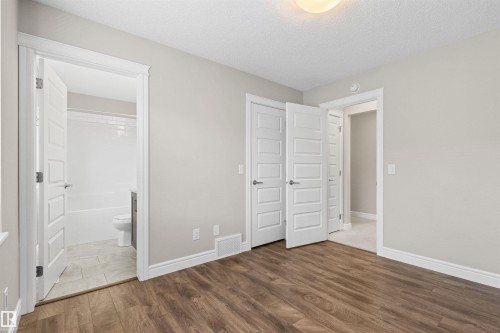 Unfurnished bedroom with light wood-style flooring, a textured ceiling, and connected bathroom - 36 330 Bulyea Road, Edmonton, AB - Indoor Photo Showing Other Room