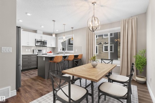 Dining area featuring a textured ceiling, a chandelier, and dark wood-style flooring - 36 330 Bulyea Road, Edmonton, AB - Indoor