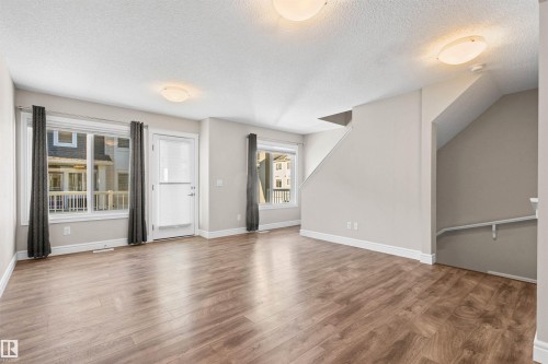 Unfurnished living room featuring a textured ceiling, healthy amount of natural light, and light wood-style flooring - 36 330 Bulyea Road, Edmonton, AB - Indoor