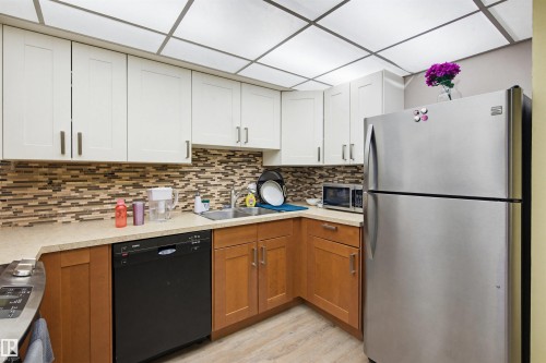 Kitchen with stainless steel appliances, light countertops, brown cabinetry, light wood finished floors, and decorative backsplash - 11108 83 Avenue Nw, Edmonton, AB - Indoor Photo Showing Kitchen With Double Sink