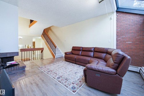 Living area featuring wood finished floors, stairway, baseboard heating, and a textured ceiling - 11108 83 Avenue Nw, Edmonton, AB - Indoor Photo Showing Living Room
