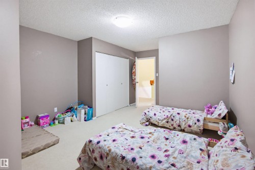 Bedroom with a textured ceiling, light carpet, and a closet - 11108 83 Avenue Nw, Edmonton, AB - Indoor Photo Showing Bedroom