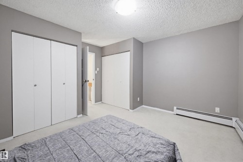 Bedroom with multiple closets, a textured ceiling, and light carpet - 11108 83 Avenue Nw, Edmonton, AB - Indoor Photo Showing Bedroom