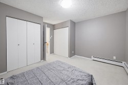 Bedroom with multiple closets, a textured ceiling, and light carpet - 