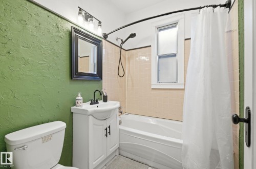 Full bath featuring a textured wall, shower / bathtub combination with curtain, and vanity - 11515 101 Street, Edmonton, AB - Indoor Photo Showing Bathroom
