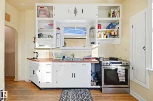 Kitchen with white cabinetry, arched walkways, open shelves, and stainless steel electric stove - 11515 101 Street, Edmonton, AB - Indoor Photo Showing Kitchen With Double Sink