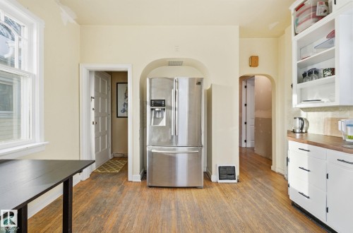 Kitchen featuring stainless steel refrigerator with ice dispenser, white cabinets, dark wood-style flooring, and arched walkways - 11515 101 Street, Edmonton, AB - Indoor Photo Showing Kitchen