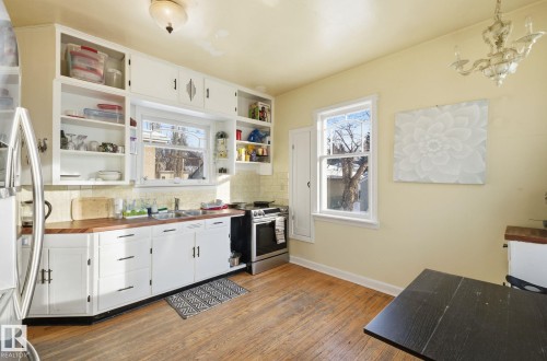 Kitchen featuring white cabinetry, open shelves, appliances with stainless steel finishes, and backsplash - 11515 101 Street, Edmonton, AB - Indoor Photo Showing Kitchen With Double Sink