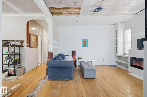 Sitting room with hardwood / wood-style flooring, built in features, arched walkways, and a glass covered fireplace - 11515 101 Street, Edmonton, AB - Indoor Photo Showing Living Room With Fireplace