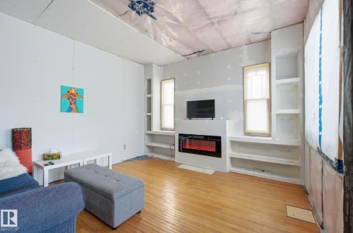 Living area with hardwood / wood-style flooring, a glass covered fireplace, and built in features - 11515 101 Street, Edmonton, AB - Indoor Photo Showing Living Room With Fireplace