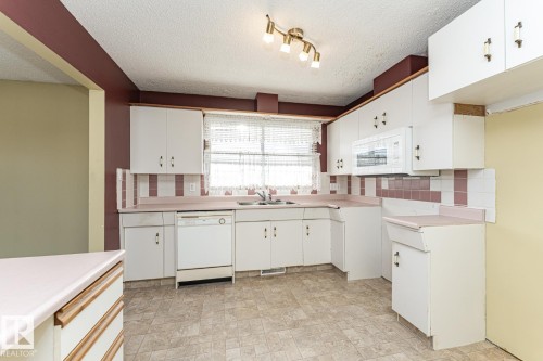 Kitchen featuring tasteful backsplash, light countertops, white cabinets, white appliances, and a textured ceiling - 10207 165 Avenue, Edmonton, AB - Indoor Photo Showing Kitchen With Double Sink