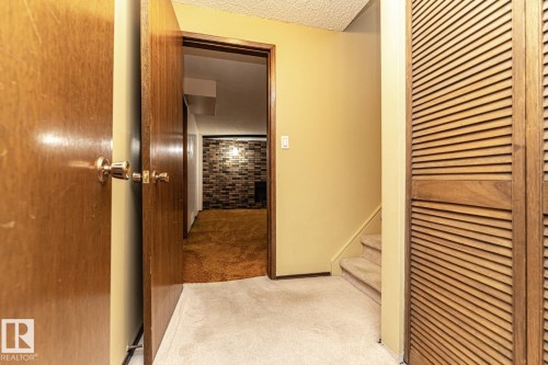 Corridor with light carpet, stairway, a textured ceiling, and brick wall - 10207 165 Avenue, Edmonton, AB - Indoor Photo Showing Other Room