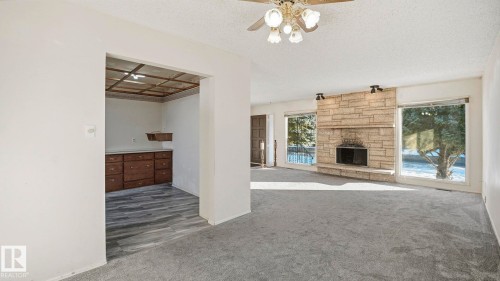 Unfurnished living room featuring carpet, coffered ceiling, a textured ceiling, a fireplace, and ceiling fan - 10478 21 Avenue, Edmonton, AB - Indoor With Fireplace