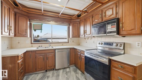 Kitchen with appliances with stainless steel finishes, light countertops, brown cabinetry, and backsplash - 10478 21 Avenue, Edmonton, AB - Indoor Photo Showing Kitchen With Double Sink