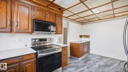 Kitchen with stainless steel electric range oven, light countertops, brown cabinetry, and black microwave - 
