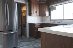 Kitchen with freestanding refrigerator, light countertops, dark wood finish cabinetry, and decorative backsplash - 