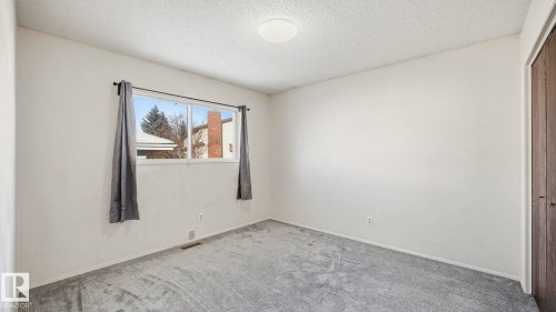 Carpeted spare room featuring a textured ceiling and baseboards - 10478 21 Avenue, Edmonton, AB - Indoor Photo Showing Other Room