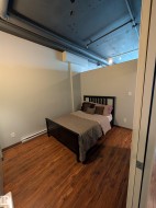 Bedroom with dark wood-style flooring and a baseboard radiator - 