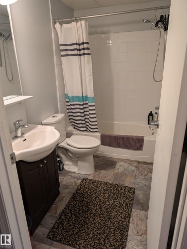 Full bath featuring vanity, shower / tub combo with curtain, and light stone finish flooring - 1013 10024 Jasper Avenue, Edmonton, AB - Indoor Photo Showing Bathroom