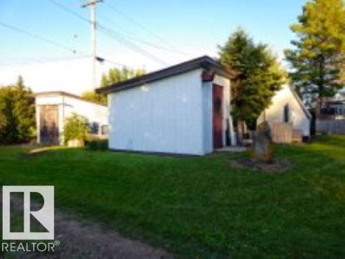 View of side of home featuring a yard and a storage unit - 4910 53 Avenue, Willingdon, AB 