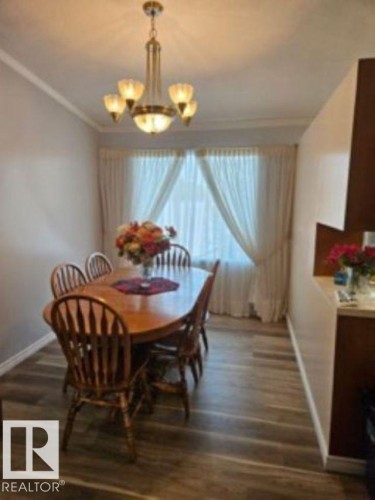 Dining area with ornamental molding, dark wood-style flooring, and a chandelier - 4910 53 Avenue, Willingdon, AB 