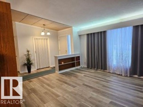 Unfurnished living room featuring wood finished floors and a chandelier - 4910 53 Avenue, Willingdon, AB 