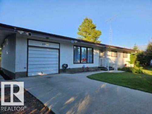 View of front of house with concrete driveway, stucco siding, a front lawn, and a garage - 4910 53 Avenue, Willingdon, AB 