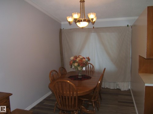 Dining room featuring dark wood finished floors, ornamental molding, and a chandelier - 4910 53 Avenue, Willingdon, AB 
