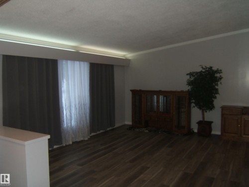 Unfurnished living room with dark wood-style flooring and crown molding - 4910 53 Avenue, Willingdon, AB 