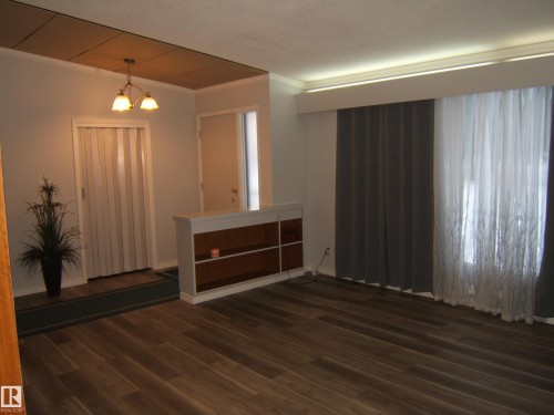 Spare room with ornamental molding, a chandelier, and dark wood finished floors - 4910 53 Avenue, Willingdon, AB 