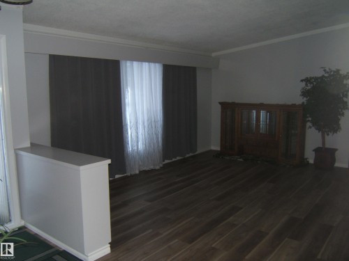 Living area with dark wood-type flooring and crown molding - 4910 53 Avenue, Willingdon, AB 