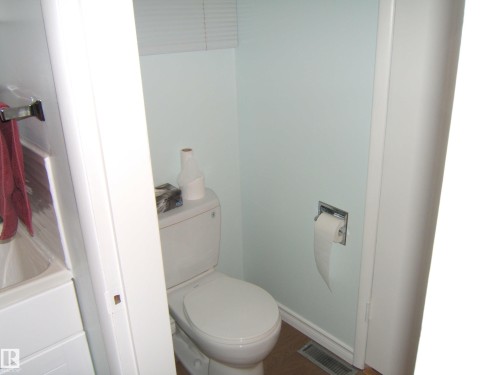 Bathroom featuring toilet and wood finished floors - 4910 53 Avenue, Willingdon, AB 
