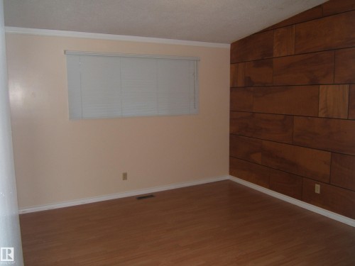 Spare room with wood finished floors and ornamental molding - 4910 53 Avenue, Willingdon, AB 