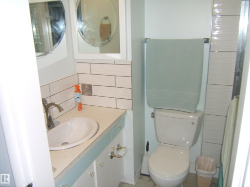 Bathroom featuring vanity, tasteful backsplash, tile walls, and a shower - 4910 53 Avenue, Willingdon, AB 