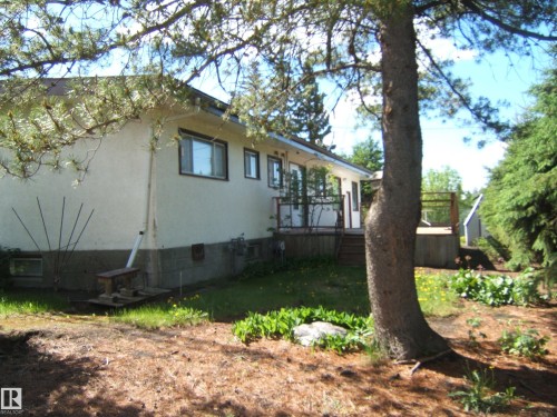 Exterior stucco siding with multiple windows and a wood deck - 4910 53 Avenue, Willingdon, AB 