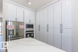 Kitchen featuring appliances with stainless steel finishes, white cabinetry, and light stone countertops - 