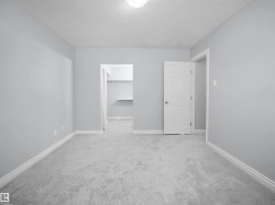 Unfurnished bedroom featuring a walk in closet, carpet floors, and a textured ceiling - 
