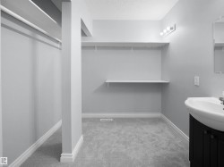 Bathroom featuring vanity, a textured ceiling, light colored carpet, and a spacious closet - 