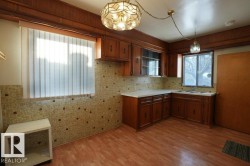 Kitchen featuring light countertops, dark wood-style flooring, brown cabinets, and decorative light fixtures - 