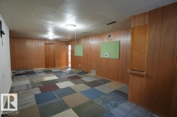 Unfurnished room featuring wood walls and dark carpet - 