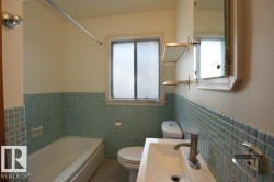 Full bathroom featuring bathing tub / shower combination, a wainscoted wall, healthy amount of natural light, tile walls, and vanity - 