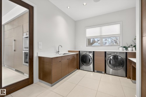 Laundry area with light tile patterned floors, recessed lighting, washer and dryer, and cabinet space - 9415 144 Street, Edmonton, AB - Indoor Photo Showing Laundry Room