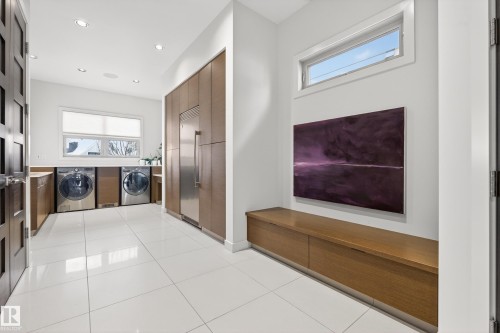 Laundry room with plenty of natural light, recessed lighting, light tile patterned floors, and cabinet space - 9415 144 Street, Edmonton, AB - Indoor Photo Showing Laundry Room