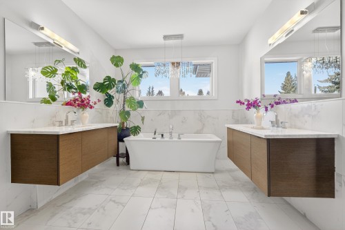 Bathroom featuring two vanities, tile walls, a soaking tub, light marble finish flooring, and a wainscoted wall - 9415 144 Street, Edmonton, AB - Indoor Photo Showing Bathroom
