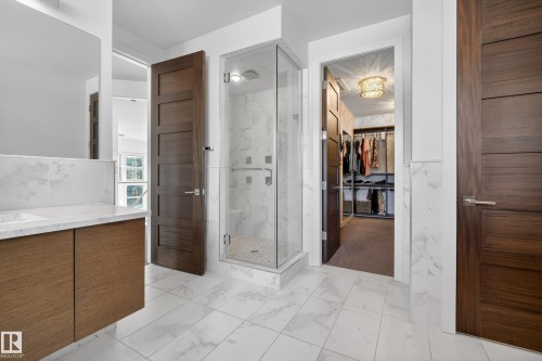 Bathroom featuring a marble finish shower, a spacious closet, light marble finish flooring, and vanity - 9415 144 Street, Edmonton, AB - Indoor